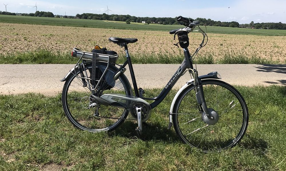 A grey step-through e-bike with a rear rack, parked on a farm track