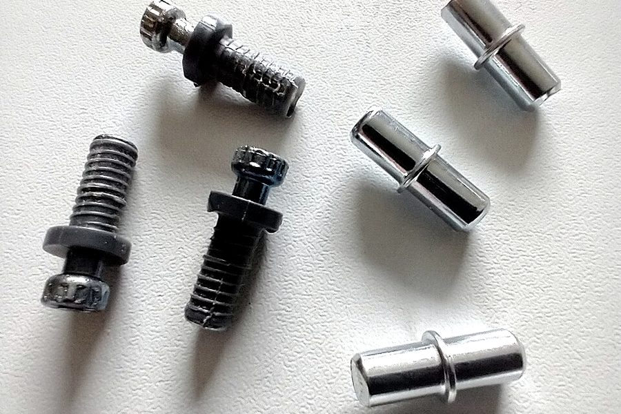 Steel shelf support pins beside two plastic plug-in pins
