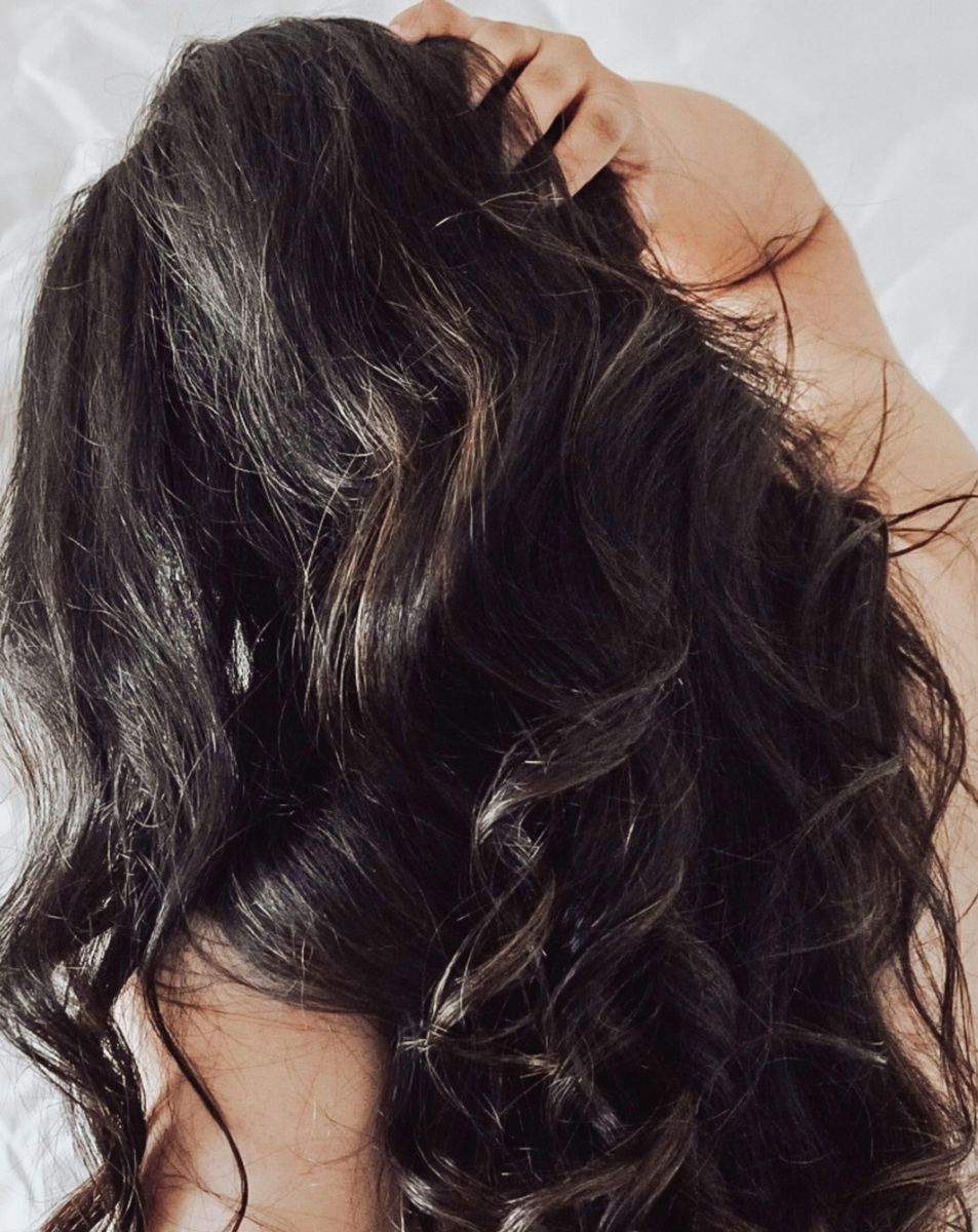 Long dark body-wave hair seen from behind, one hand running through it