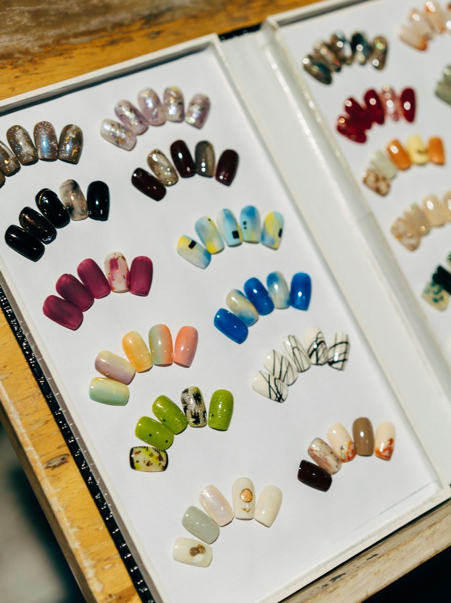 An open display box holding rows of press-on nail sets in many colours and finishes